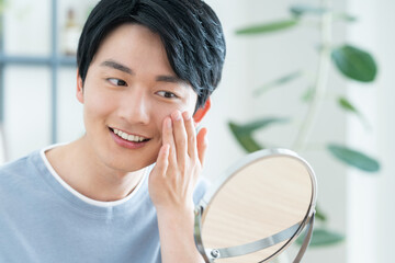 鏡で肌の確認をする若い日本人の男性