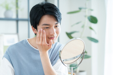 鏡で肌の確認をする若い日本人の男性
