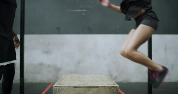 People, fitness and jumping on box for workout, exercise or training together at the gym. Active young man and woman or bodybuilders in jump or teamwork for cardio, health and wellness at indoor club