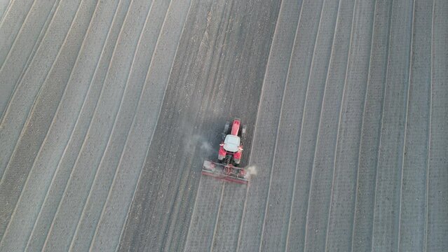 drone image taken from above, moving away from the working tractor in the field