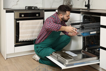 Serviceman repairing dishwasher cutlery rack in kitchen