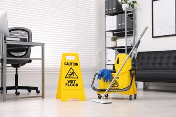 Cleaning service. Mop, wet floor sign and bucket with supplies in office