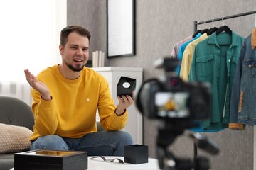 Smiling fashion blogger showing wristwatch while recording video at home