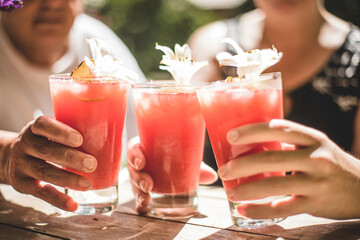 Primer plano de brindis entre dos personas, con bellos tragos rojos