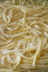 Spaghetti in pan cooking in boiling water.