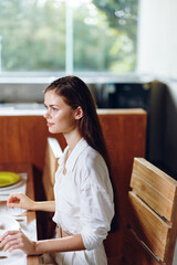 Smiling woman enjoying a romantic dinner at home with a delicious meal on the elegant dining table The table is beautifully set with a plate of homemade cake, trendy decorations, and a glass of wine