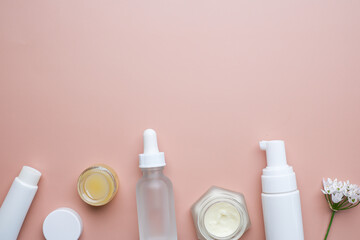 The skincare and cosmetic with flower on pink or neutral flatlay background - obrazy, fototapety, plakaty