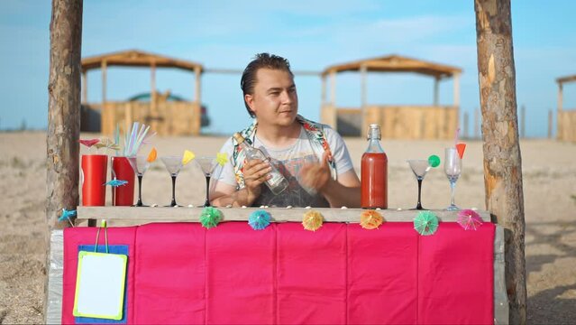 Bartender mixes cocktail inviting beachgoers to bar. Man smilingly makes drinks for pleasure of holidaymakers on beach in summer