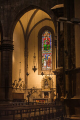 Dark interior of the Santa Maria del Fiore cathedral with candelabra suspended over the illuminated...