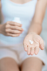 woman hand holding medicine painkiller pill on the sofa at home, taking for headaches, stomach ache, Diarrhea Pain from food poisoning, Endometriosis, Hysterectomy and Menstrual