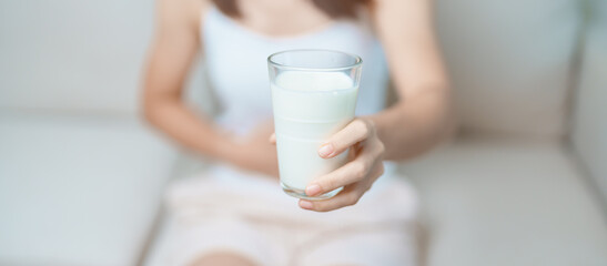 Fototapeta na wymiar Lactose intolerance and Milk allergy concept. woman hold Milk glass and having abdominal cramps and pain when drink Cow Milk. Symptom stomach ache, Dairy intolerant, Nausea, Bloating, Gas and Diarrhea
