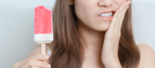 Teeth Sensitive to Cold concept. woman hold Ice cream and having toothache and pain after eat. Tooth Decay or Gum Disease, Grinding Teeth and Stress, Exposed Nerve Roots, Crack and Receding Gums