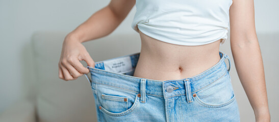 young slim female wearing big or oversize jeans, woman show healthy shape after weight loss....