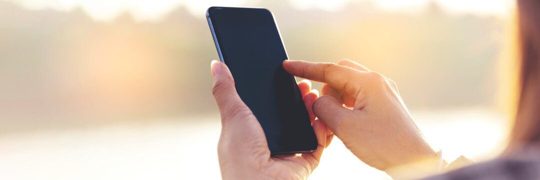 Banner Woman hands holding mobile phone outdoor surfing internet online technology lifestyle. Close up woman hand using smartphone gadget text message panoramic with copy space. Technology lifestyle