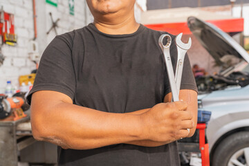 Close-up of strong arm of a mechanic holding tools