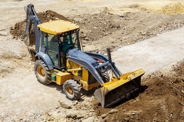 A large yellow and black construction vehicle is digging a hole