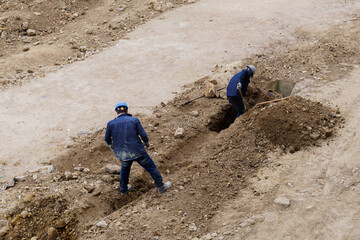 Two men are digging a hole in the dirt