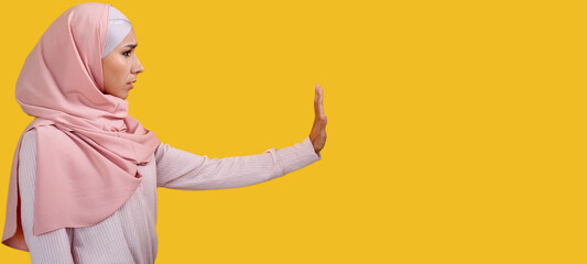 Stop gesture. Refusal no. Rejecting disagreement. Disturbed scared worried woman in hijab warning with enough hand sign isolated on yellow empty space background. - obrazy, fototapety, plakaty