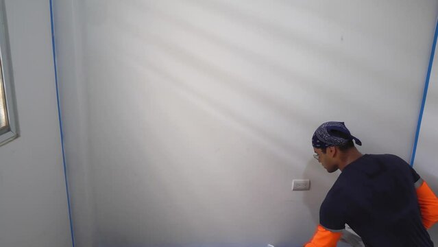 The Man is Applying White Paint to the Interior Wall of the House - Static Shot