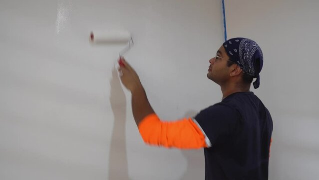 Man Using Roller To Paint White Color On The Wall - Close Up