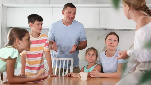 Concept of big friendly family - children of different ages and parents communicate in the home kitchen