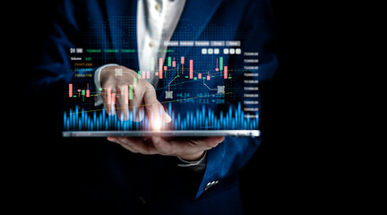 Businesswomen use digital tablet to analyze virtual screens of graph stock market changes for...