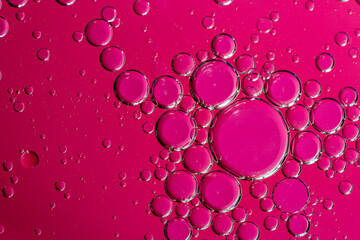 Abstract fuchsia pink background with water bubbles in oil.