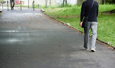 春の公園の新緑と散歩するシニア男性の姿