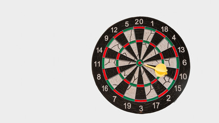 A n old dartboard against a white background with a yellow dart arrow hitting bullseye on it