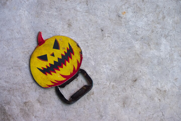 Metal bottle opener with Jack-O'-Lantern pumpkin head handle on a white marble table