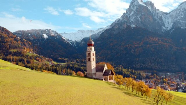 4k drone flight moving to the side footage (Ultra High Definition) of St. Valentin ( Kastelruth ) church with Petz peak on background. Niceautumn scene of Kastelruth village, South Tyrol, Italy.