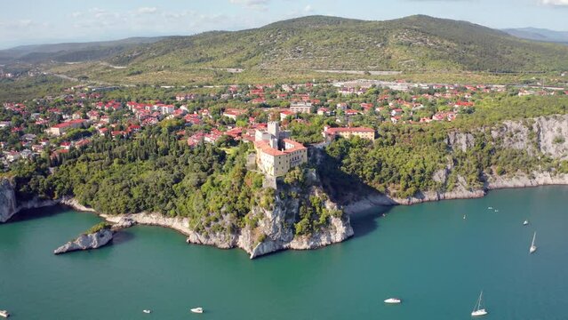4k drone flight moving to the side footage (Ultra High Definition) of Duino Castle. Sunny morning scene of Adriatic coast of Italy. Beautiful cityscape of Duino town. Traveling concept background.