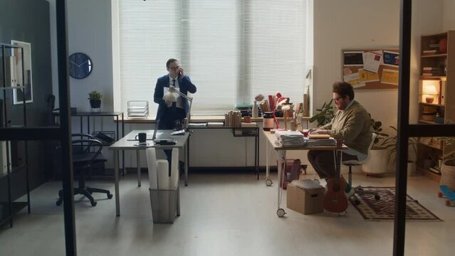Full timelapse shot of two Caucasian colleagues working at shared office - annoying slacker playing guitar, fooling around, perfectionist in suit using laptop, making phone calls, hitting him on headF