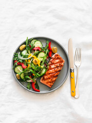 Delicious diet lunch, dinner - grilled salmon and fresh vegetable salad on a light background, top view - 791307671