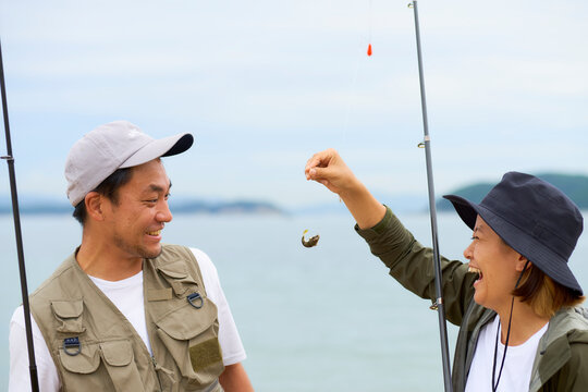 釣れた小さい魚を見てはしゃぐ男女