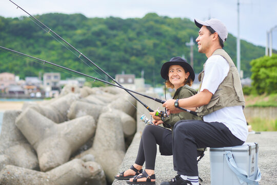 堤防で座って釣りをする男女