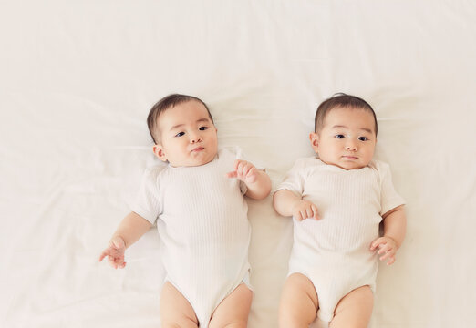 ベッドに寝転ぶ双子の赤ちゃん