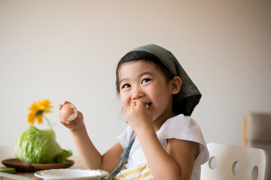 エプロン姿で茹で卵を剥いている女の子