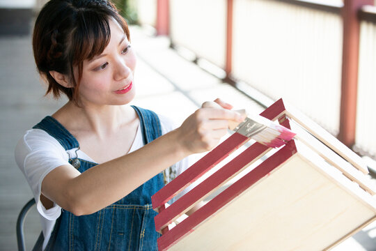 刷毛で箱に色を塗っている女性