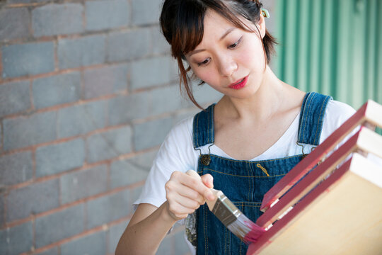 刷毛で箱に色を塗っている女性