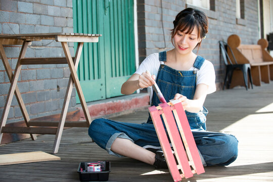 刷毛で箱に色を塗っている女性