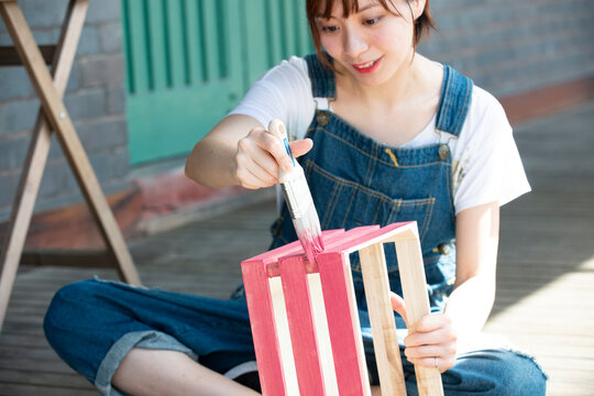 刷毛で箱に色を塗っている女性
