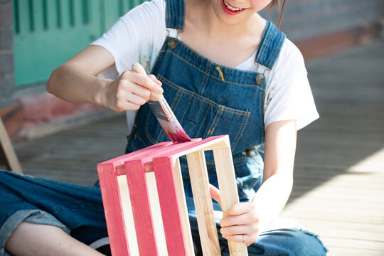 刷毛で箱に色を塗っている女性の手元