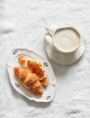 Delicious breakfast, brunch, snack - cappuccino and croissant cottage cheese, egg, red caviar sandwich on a light background, top view - 791313004