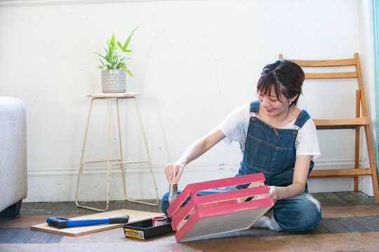 刷毛で箱にペンキを塗っている女性