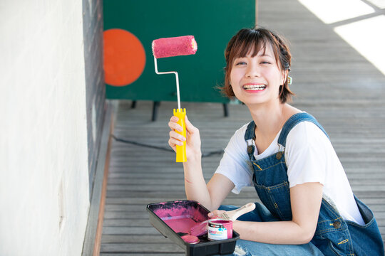 ペイントローラーを持って笑っている女性