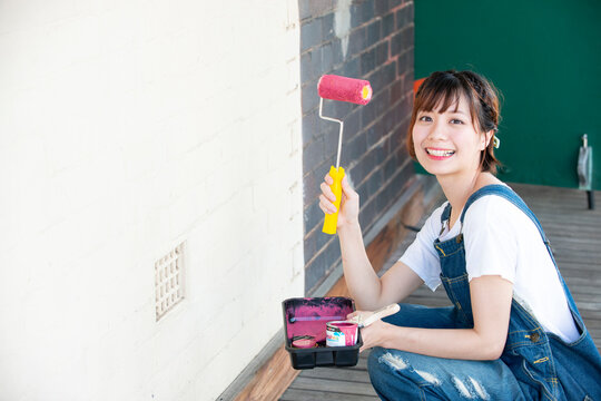 ペイントローラーを持って笑っている女性