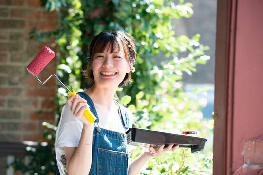 ペイントローラーを持って笑っている女性
