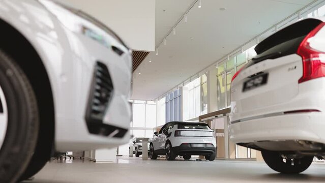 Exterior of new brand fully electric suv car in light dealership. Battery charger in white electric car based in modern showroom with panoramic windows.
