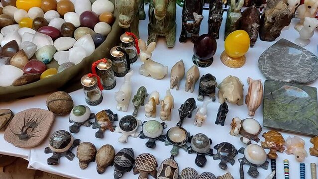 Various stone figures and animals for sale on a tablecloth